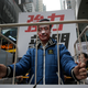 A protester wearing a mask of missing bookseller Lee Bo sits in a cage.